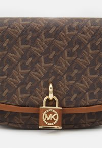 Brun monogrammerad handväska med texturerad tyg, guldfärgade detaljer och lås med logotyp. Har ett slätt brunt band i botten.