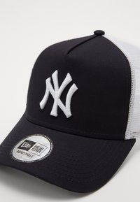 Schwarze und weiße verstellbare Baseballmütze mit einem auffälligen weißen gestickten "NY"-Logo, einem strukturierten schwarzen Frontteil und weißen Netzseiten.