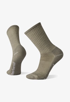 Olivenfargede ribbestrikkede sokker med forsterket tå og hæl, midt på leggen, laget av et teksturert materiale, med en logo på siden.