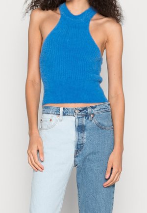 Blauwe fluffy gebreide haltertop met geribbelde textuur, cropped ontwerp, gecombineerd met denim jeans in twee tinten met lichte en donkere wassingen.
