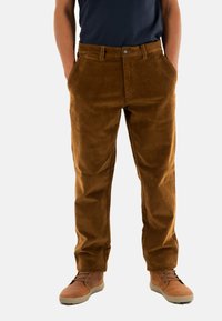 Bruine corduroy broek met een recht model, voorzakken en een knoopsluiting. Gemaakt met lichtbruine schoenen.