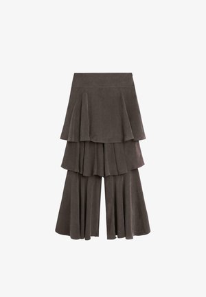 Pantalon large gris foncé à couches superposées ressemblant à une jupe, avec des panneaux de tissu plissés et une taille haute sur fond blanc.
