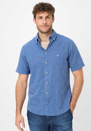 Camicia a maniche corte con bottoni in blu e bianco a righe, tessuto leggero, taschino sul petto, colletto classico, abbinata a jeans in denim blu.