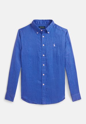 Camisa azul de linho com colarinho abotoado, botões cor-de-rosa e logótipo bordado no peito. Mangas compridas com barra arredondada.