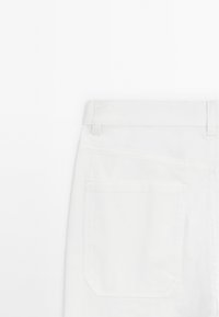 Vita jeans i denim med rak skärning, utrustade med en enda bakficka och synliga bältesöglor. Slät textur och minimal sömnadsdetalj.