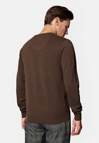 Brązowy sweter z dzianiny z długimi rękawami, okrągłym dekoltem i prążkowanym wykończeniem. Teksturowany materiał i gładkie wykończenie z tyłu.