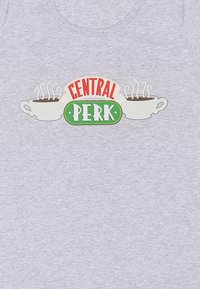 Šedé tričko s potištěným designem s textem "CENTRAL PERK" v červené a zelené barvě, a dvěma šálky kávy, z nichž stoupá pára. Měkká textilie.