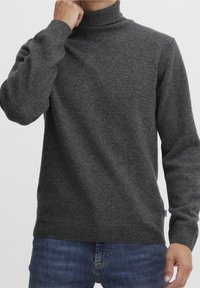 Pull-over gris foncé à col montant, poignets et ourlet côtelés. Fabriqué en tissu texturé, il épouse étroitement le torse et les bras.