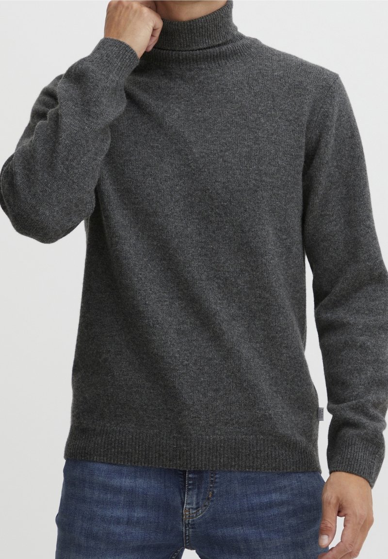 Pull-over gris foncé à col montant, poignets et ourlet côtelés. Fabriqué en tissu texturé, il épouse étroitement le torse et les bras.