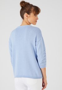 Maglione azzurro chiaro lavorato a maglia con maniche in pizzo a tre quarti, scollatura rotonda e una vestibilità leggermente rilassata. Tessuto morbido, design casual.