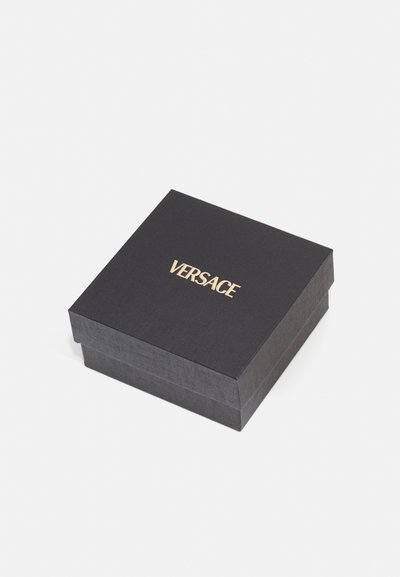 Mustaline tekstuuriga must kinkekarp, mille peal on kuldne "VERSACE" logo, ruudukujuline ning sujuva kaanega.