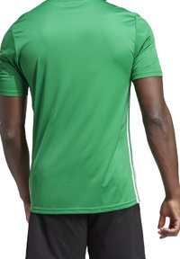Maglietta sportiva verde realizzata in tessuto morbido, con un design aderente, maniche corte e dettagli bianchi lungo i lati.