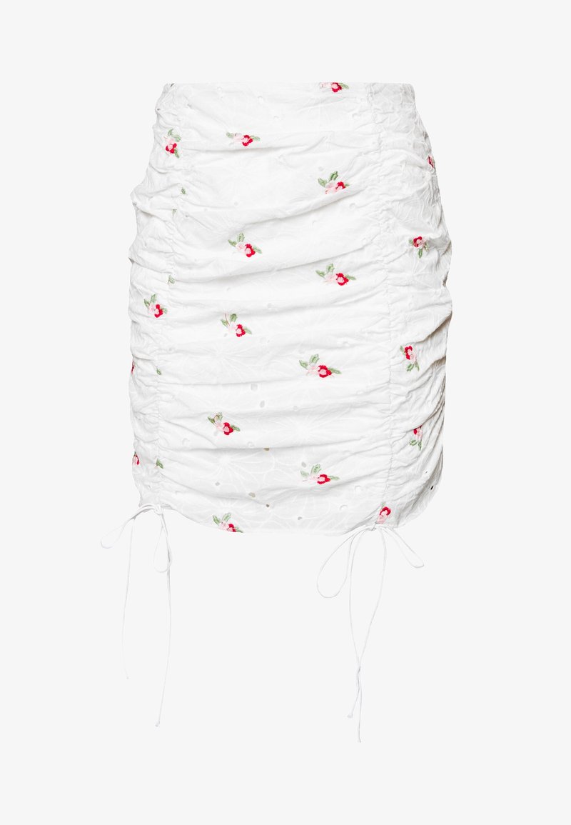 Mini-jupe blanche froncée avec une petite broderie florale rouge et rose et des cordons réglables des deux côtés.