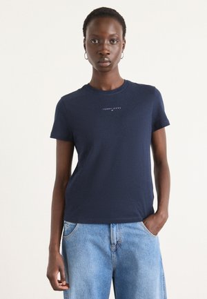 Marineblå bomull T-skjorte med korte ermer, rund hals og logoetrykk over brystet. Kombinert med lyseblå denimbukser.