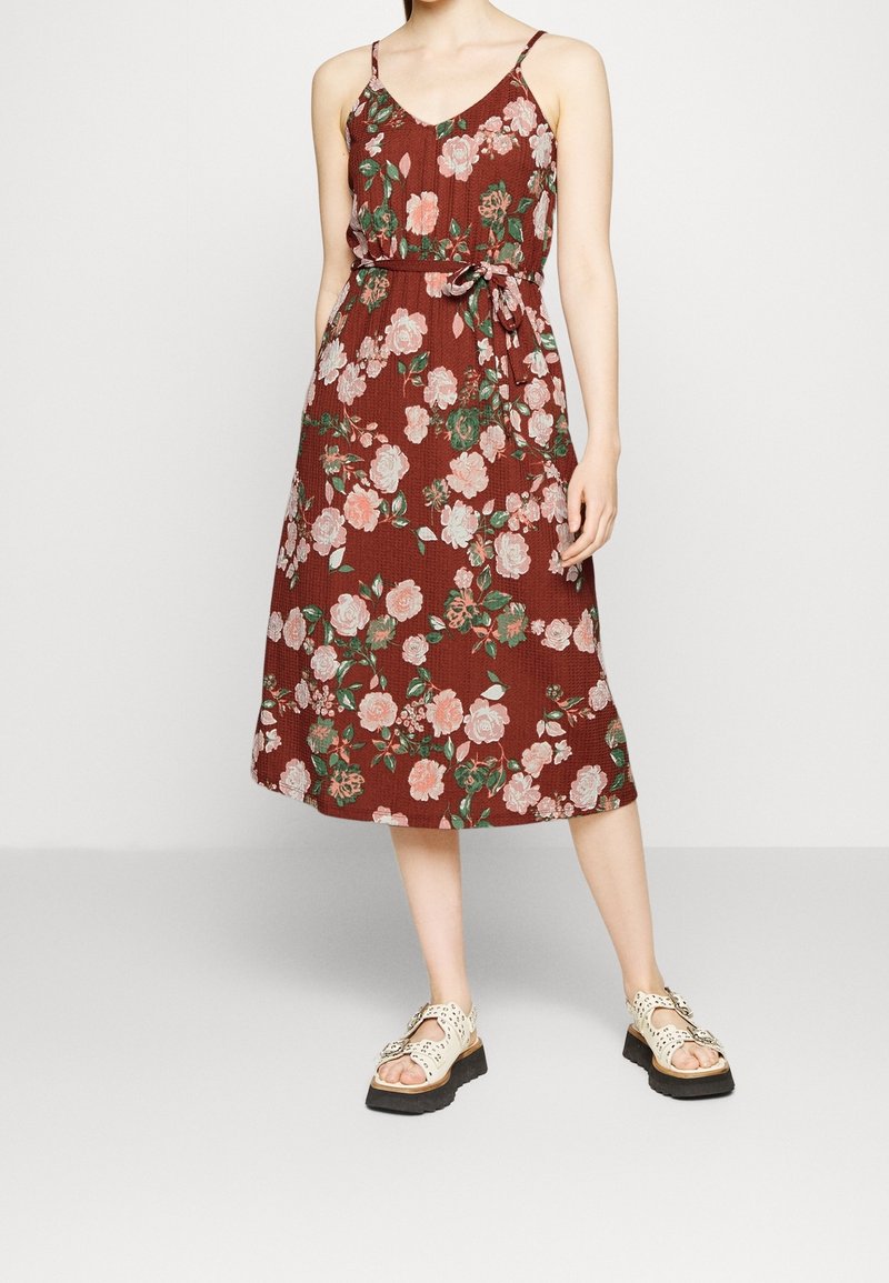Viininpunainen kukkamekko, jossa on spagettiolkaimet, vaaleanpunaisia ja vihreitä ruusukuvioita, naru vyötäröllä ja puolipitkä, teksturoitu kangas.