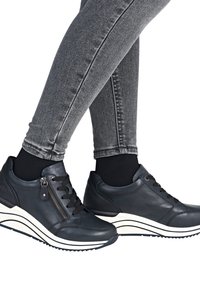 Leder-Sneaker in dunklem Marineblau mit strukturiertem Finish, ausgestattet mit schwarzen Schnürsenkeln und einem seitlichen Reißverschluss. Dicke weiße Sohle mit schwarzen Streifen.