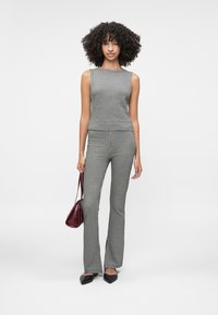 Black and white houndstooth patterned sleeveless top and fitted pants, paired with a maroon handbag and black pointed-toe flats.