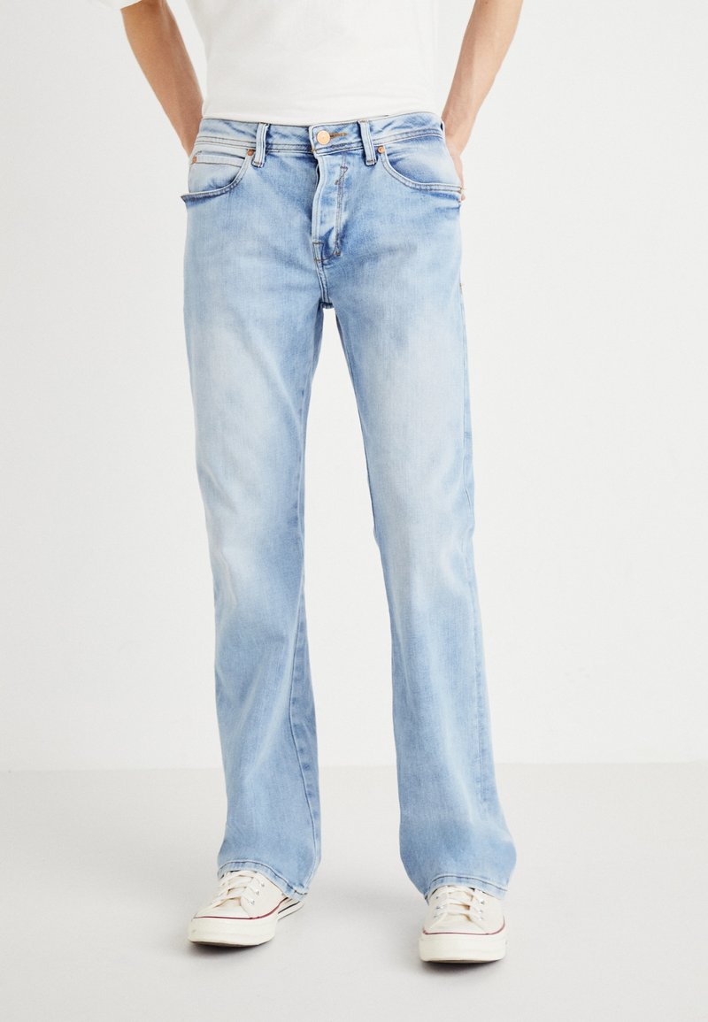 Vaqueros de denim azul claro con corte recto, que presentan un estilo clásico de cinco bolsillos y detalles de costura visibles.