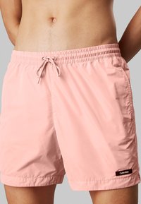 Pantaloni da nuoto rosa realizzati in materiale morbido e leggero. Presentano una vita elasticizzata con cordino e un piccolo logo del marchio.