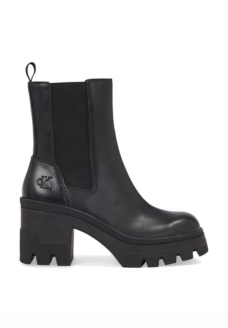 Botas de tobillo de cuero negro con paneles elásticos laterales, tacón de goma grueso y suela detallada. Presenta un acento de logo en el tacón.