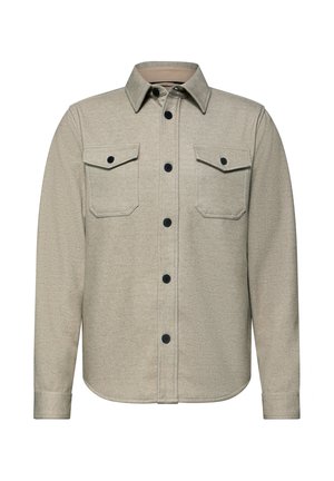Chemise beige tissée avec col, deux poches poitrine et boutons noirs. Texture douce avec une coupe droite et un ourlet arrondi.