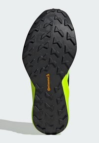 Suola in gomma nera con un motivo di battistrada multidirezionale, caratterizzata da accenti laterali di un brillante verde e da un prominente logo arancione "Continental".
