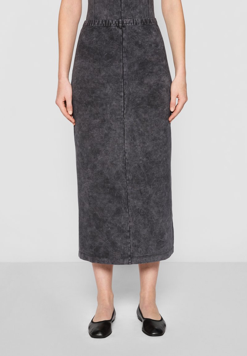 Svart denim midi-skjørt med strukturert overflate, med høy midje og synlig søm, kombinert med flate svarte sko.