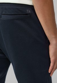 Marineblauwe katoenen broeken met een gestructureerde afwerking, voorzien van een slim fit, een achterzak en een subtiele merkaccent bij de tailleband.