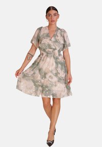 Vestido con estampado floral, mangas cortas tipo volante, cintura fruncida y falda a la altura de la rodilla. Los colores incluyen verde, rosa pálido y acentos dorados.