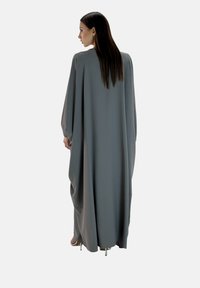 Długa, luźna szara sukienka o wysokim dekolcie, szerokich rękawach i gładkiej teksturze. Posiada dół sięgający do podłogi i minimalistyczny design.