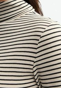 Suéter de cuello alto con rayas en blanco y negro, textura acanalada, diseño ajustado, cuello alto, con rayas horizontales estrechas.