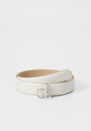 Witte leren riem met een gladde textuur en een zilverkleurige gesp met een "ck" logo. Verstelbare lengte met een strakke design.