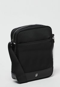 Borsa a tracolla nera in nylon con una texture liscia, chiusura con zip e tasca frontale. Caratterizzata da una tracolla imbottita e un accento con logo.