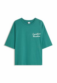 Teppe bomulds t-shirt med korte ærmer, rund halsudskæring og hvid tekst, der står "Lokation: Ferie" på forsiden. Afslappet pasform.