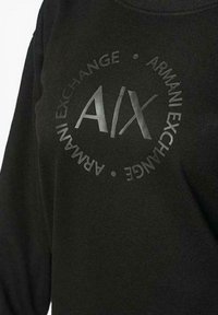 Felpa nera con design frontale che presenta il testo "ARMANI EXCHANGE" e "A|X" in un layout circolare, tessuto testurizzato.