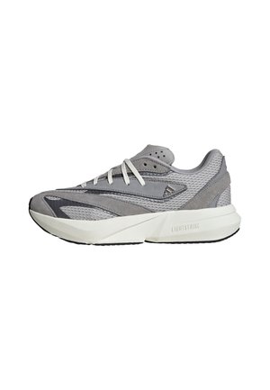 Baskets de sport grises et blanches avec des panneaux en mesh et suède, lacets blancs et semelle épaisse et rembourrée portant la mention "LIGHTSTRIKE."