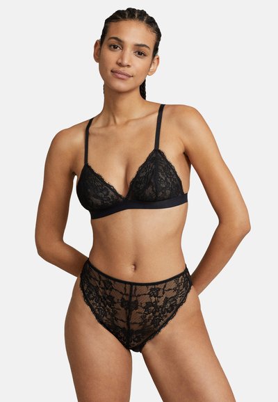 Czarny koronkowy bralette z regulowanymi ramiączkami i falbaniastym wykończeniem, w połączeniu z pasującymi koronkowymi majtkami z wysokim stanem, zdobionymi wzorami kwiatowymi.