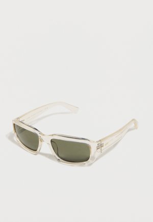 Lunettes de soleil rectangulaires avec montures beige transparent et verres teintés foncés, présentées sur un fond blanc uni.