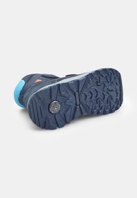 Suela de zapato de senderismo azul, con un patrón de relieve resistente, material de goma duradera y un detalle circular cerca del centro.