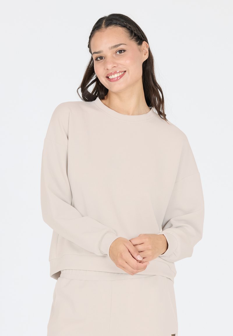 Light beige sweatshirt made of soft fabric, featuring a crew neckline, dropped shoulders, and long sleeves with ribbed cuffs.