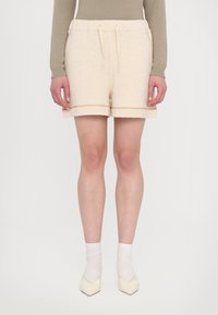 Lys beige bomull-blanding shorts med elastisk midjebånd og snor. Har oppbrettede sømmer med dekorativ brodering. Glatt tekstur.