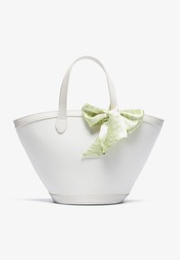 Hvid lærredstotebag med buet form, læderhåndtag og en grøn mønstret sløjfeaccent på siden.