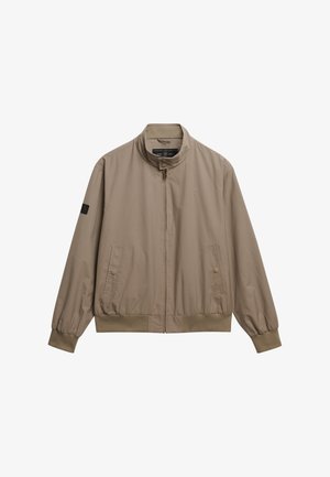 Lys beige bomberjakke med stående krave, lynlås foran, elastiske manchetter og kant. Har sidelommer og et diskret logo patch.