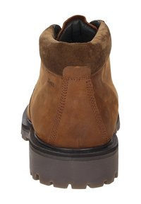 Stivaletto in suede marrone con punta arrotondata, superiore testurizzato e suola in gomma resistente con scanalature profonde per una migliore presa.