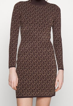Robe marron à manches longues ajustée avec un motif all-over du logo MK en beige, col montant, portée par une personne debout les mains relâchées le long du corps.