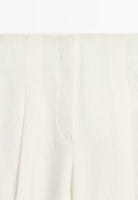 High-waist cream-colored wide-leg pants with a clean front and subtle seam detailing.