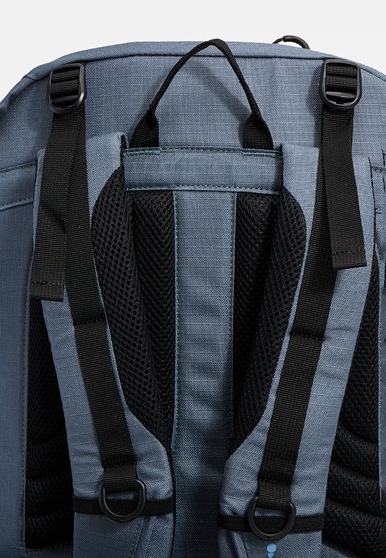 Blauer Rucksack mit gepolstertem schwarzen Mesh-Rückenpanel, verstellbaren schwarzen Schnallen, einem Tragegriff oben und zwei D-Ringen an den Riemen.