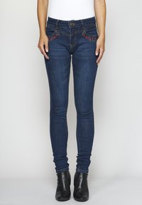 Tummansiniset skinny-farkut, joissa on kukkakoristelu etutaskuissa, valmistettu denimsistä, joissa on klassinen vyötärö ja istuva siluetti.