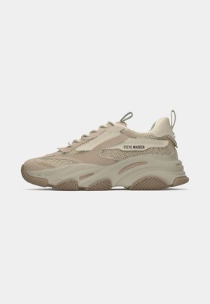Beige sneaker featuring mesh and suede overlays, prominent cushioning sole, textured accents, and a logo on the side.