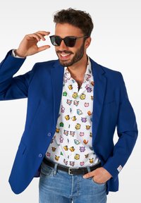 Mėlynas švarkas su dviem mygtukais, dėvimas ant baltos marškinės, papuoštos spalvingais pikseliais pieštais animacinių filmų personažais. Sukomplektuota su tamsiais akiniais nuo saulės ir džinsais.